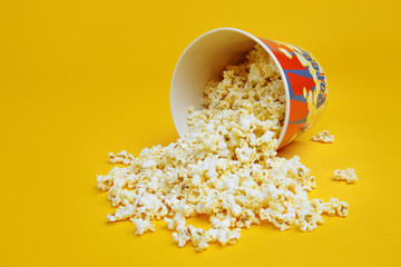 Popcorn spilled from a bright box isolated on yellow background.
