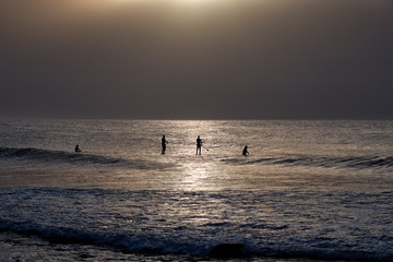 Fototapeta na wymiar Surfer and sup surfers silhouette in the water at sunset with sea background