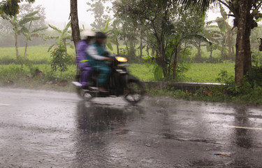 Fast motorcycle with riders blur during heavy rain