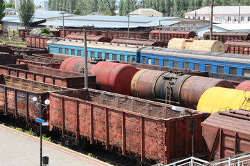 Old and rusty railway cars and trains are standing at the station. Commodity and passenger cars.