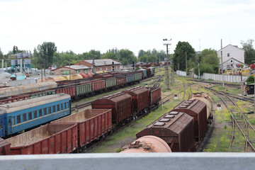 Old and rusty railway cars and trains are standing at the station. Commodity and passenger cars.