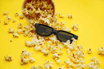 Popcorn in a bowl and 3d glasses on yellow background. Entetainement concept.