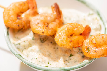 close up view of delicious fried prawns on skewer with sauce
