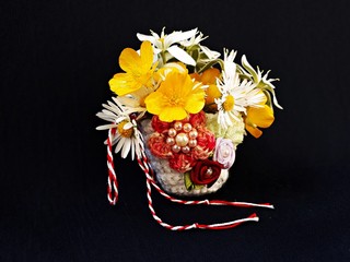 Handmade crocheted basket with spring flowers and red and white string, known as Martisor, it is a...