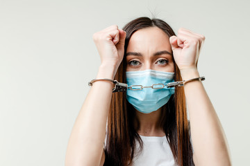 woman with handcuffs wearing mask isolated on white background. quarantine concept