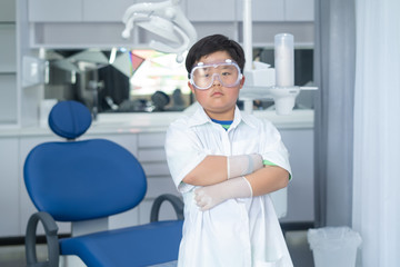Fototapeta na wymiar Little Asian doctor dentist boy with a dentist suit, standing in the dentist clinic.