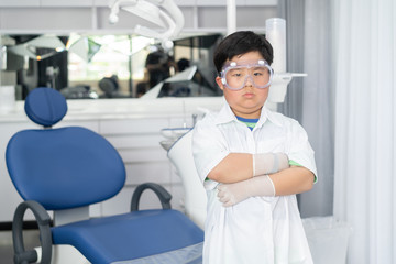 Little Asian doctor dentist boy with a dentist suit, standing in the dentist clinic.