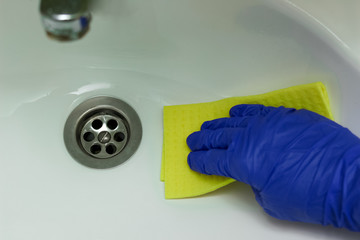 Female hand with sponge cleaning a sink in the bathroom