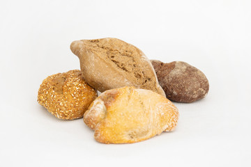 Batch of various baked breads. Fresh loafs made of wheat and rye flour isolated on white background. Studio shot. Side view. Homemade bakery and cooking at home concept