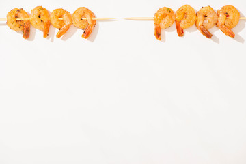 top view of delicious fried prawns on skewers on white background