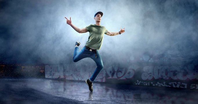 Male street dancer in action with a graffity wall behind the fog on a backgroung.