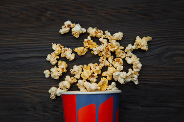 Popcorn spilled from a bright box isolated on wooden background.