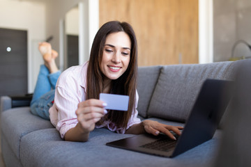 Pretty woman makes purchases through the internet holding credit card. Shopping at home.