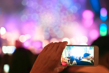 Close up of recording video with smartphone during a concert. colorful crowd on concert, disco...