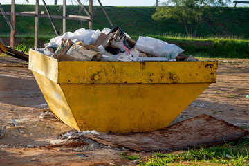 Yellow dump loaded near a construction site, home renovation dump full of construction rubbish dumps