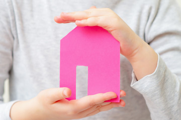 Paper house in hands of child dreaming of home. Family and home concept.