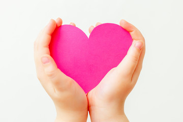 Fototapeta premium Closeup of paper heart in little hands of child on white background. Pink heart in hands on white.
