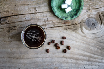 Obraz na płótnie Canvas Kaffee in einem Glas und ein Teller mit Würfelzucker auf einem grauen Holztisch. Rustikaler Stil, Espresso, Draufsicht.