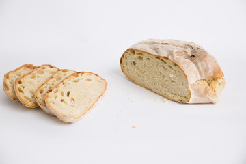 Cut loaf of wheat bread, bread crumbs and slices. Closeup shot. Isolated object on white background. Homemade food or breakfast concept