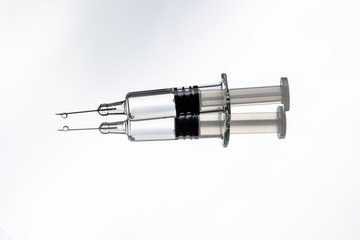 Glass syringe with reflection on white background. Concept about vaccine of coronavirus or COVID-19.