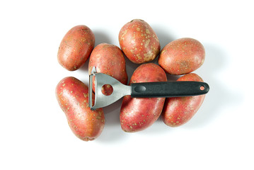 a pile of unpeeled potatoes and black potatoes peeling, white background, object isolated. potato and peeler