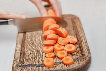 Cutting carrots and other vegetables with a kitchen knife on a wooden Board