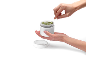 female hands are holding a white jar and using a natural green face cream or mask isolated on white...