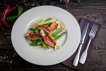 Grilled fish fillet with asparagus, sauce on a dark background