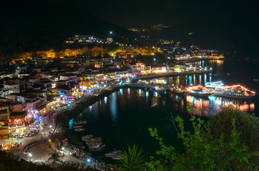 Fototapeta na wymiar the city of Parga, by the mediterranean sea, with it's houses and boats in the pier, at night