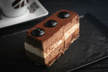 French mousse dessert, with chocolate on a black plate and a dark background