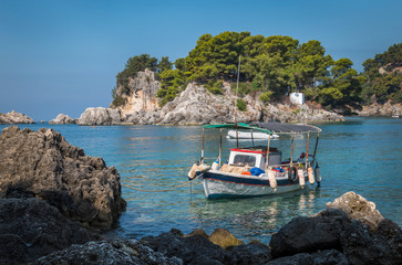 in the bay of Parga, an island and a chapel, boats are waiting on the blue Mediterranean sea,