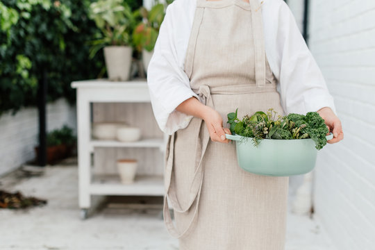 woman with a casserole filled with garden green vegetables and herbs