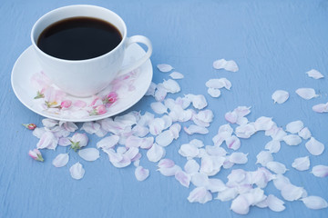 around a cup of coffee rose petals on a blue style. Top view
