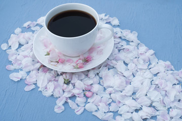 around a cup of coffee rose petals on a blue style. Top view
