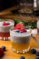 mango mousse with berries and powdered sugar on a wooden table