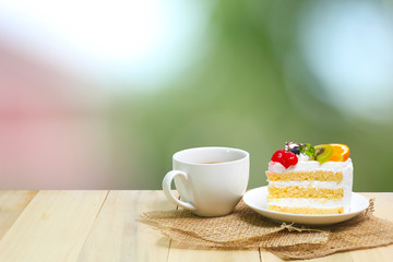 Obraz na płótnie Canvas Slice cake with coffee cup on wood , green blur background