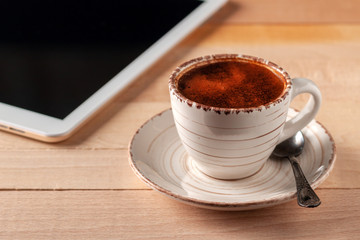 Digital tablet and coffee cup on wooden table