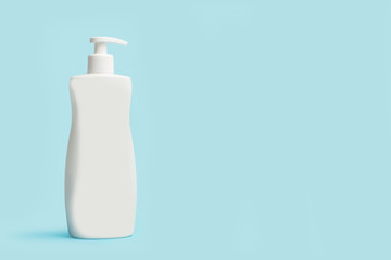 Frasco dispensador de crema para el cuerpo sobre un fondo celeste liso y aislado. Vista de frente....