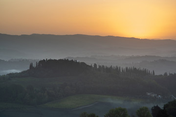 Tuscany landscape at sunrise. Typical for the region tuscan farm house, hills, vineyard. Italy