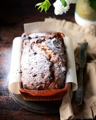 Curd cake with raisins on a cutting board on a dark background with lilac flowers