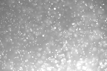White glitter vintage lights background. White bokeh on black background.