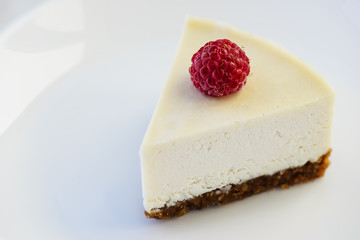 Slice of raw almond cake with raspberries on a white plate. Healthy food concept. Lactose free, gluten free, sugar free.