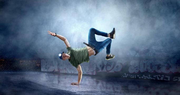 Male street dancer in action with a graffity wall behind the fog on a backgroung.