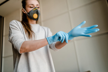 woman wearing medical gloves and respirator mask at home