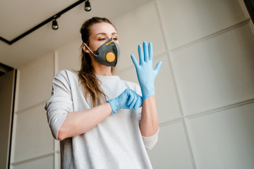 woman wearing medical gloves and respirator mask at home