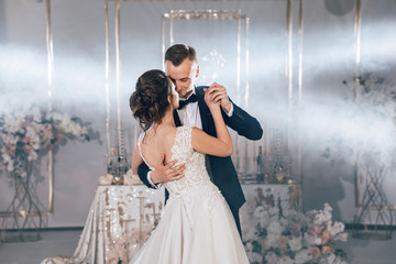 First wedding dance indoors or in a restaurant. Wedding couple bride and groom are dancing. Lighting effects, architectural light. The bride and groom in a dance. Full-length photo.