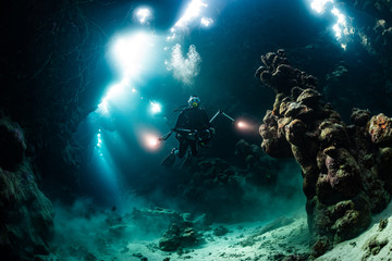 typical underwater cave in a red sea reef with an underwater photographer diver