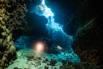 Obraz na płótnie Canvas typical underwater cave in a red sea reef with an underwater photographer diver