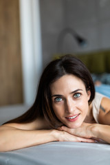 Happy pensive young woman lying and thinking on bed. Thoughtful beautiful girl lying on bed while looking up.