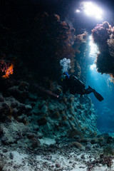 Fototapeta na wymiar typical underwater cave in a red sea reef with an underwater photographer diver